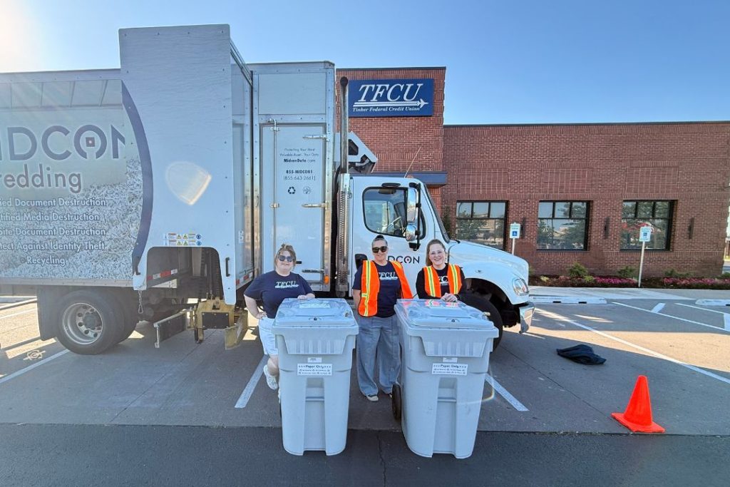 TFCU employees stand by trash cans in front of a large truck