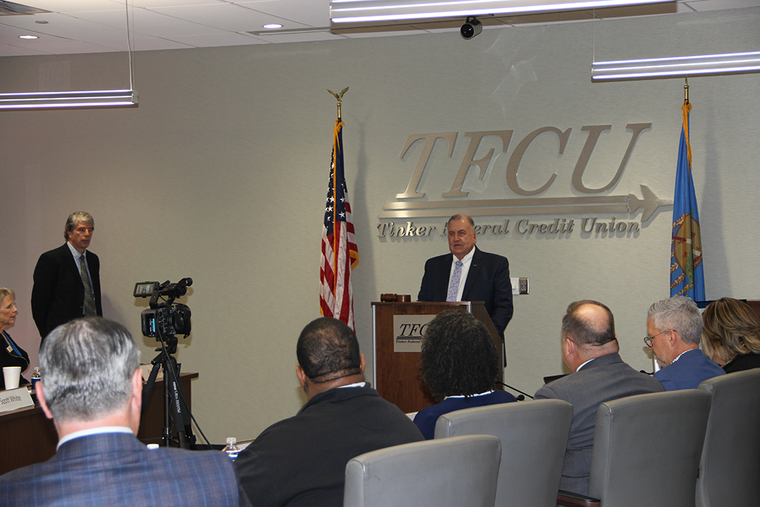 A TFCU board member speaking at a podium with members sitting around a table.