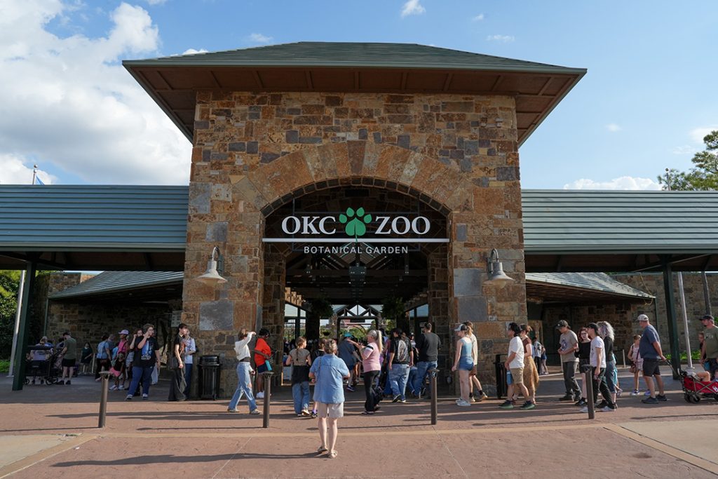 Front of OKC Zoo with people standing in front of the entrance.