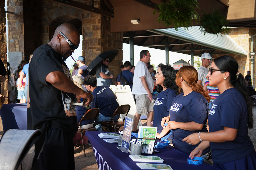 FCU employees talking to a member at the entrance of the zoo for member appreciation.
