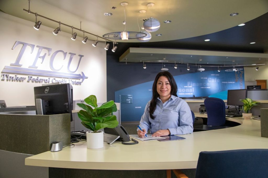 A TFCU employee sits at the front desk of a branch
