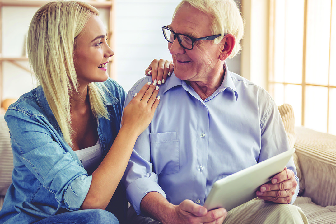 An older man and younger woman are using a digital tablet