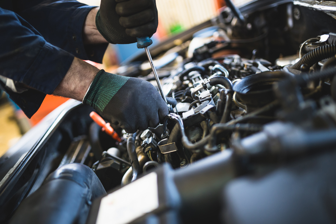 Close up of mans hands working on a vehicle engine