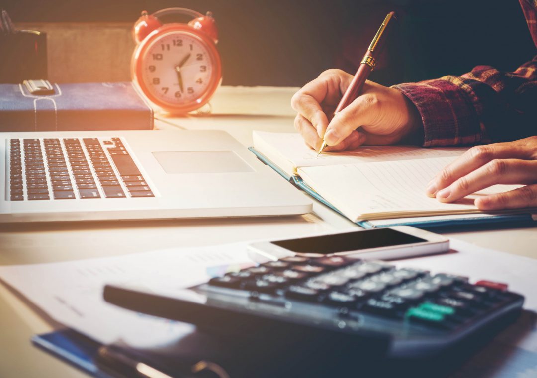 Person making their own budget on paper with pencil.