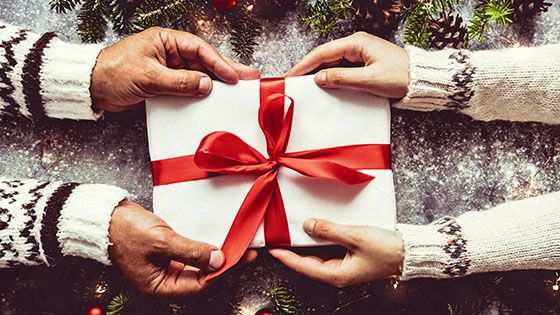 Close up of two pair of hands holding a gift box.