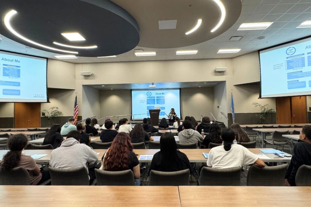 A group of people sit and listen to a financial education workshop