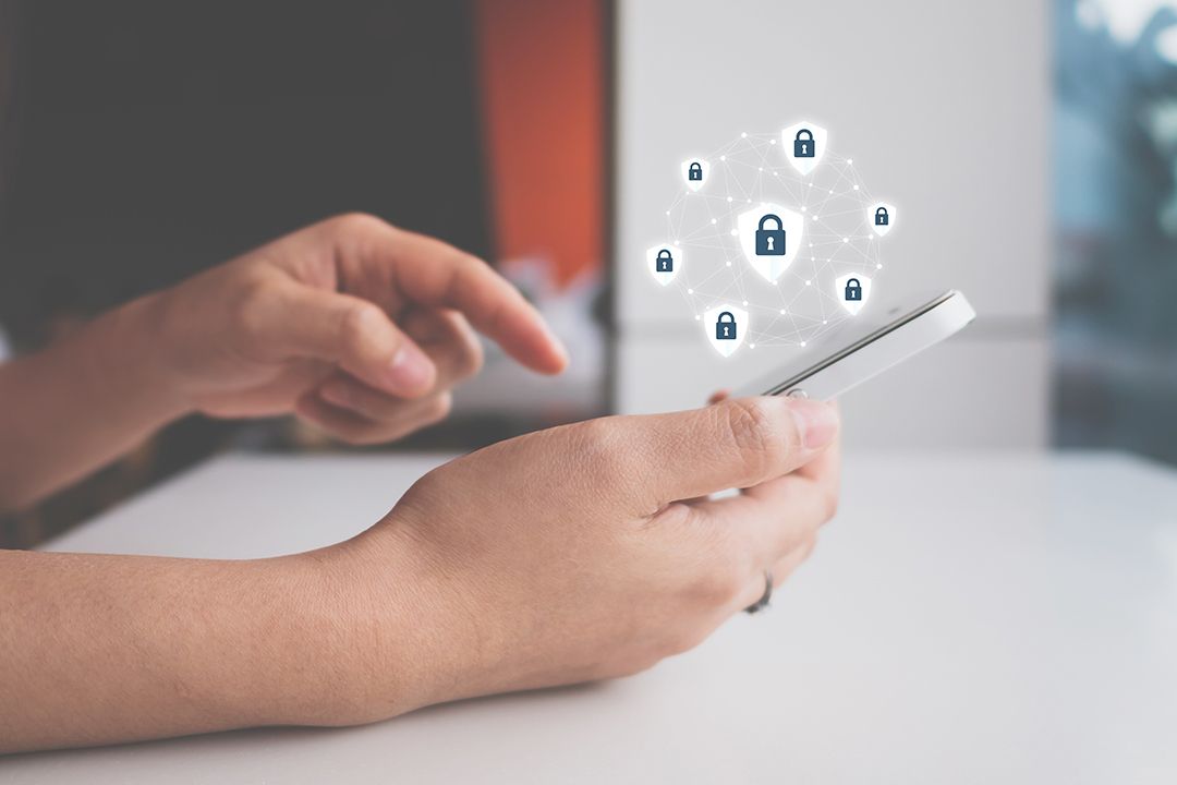 Close up of a woman's hands as she's holding a smartphone with lock and shield icons hovering on top.