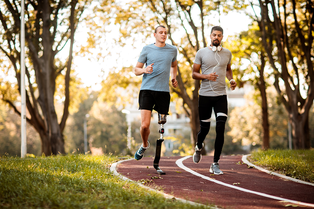 Two young men jogging on a trail surrounded by trees.