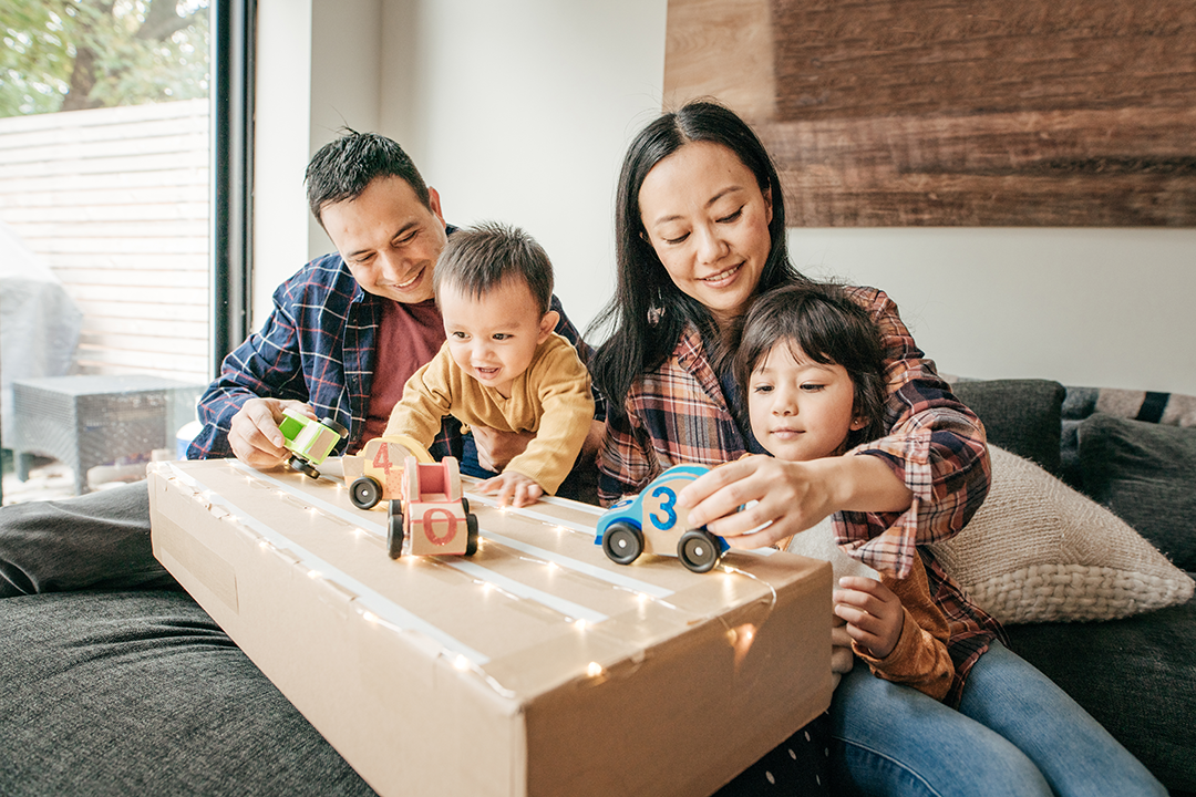 A mom and dad playing with toys with their two younger kids.