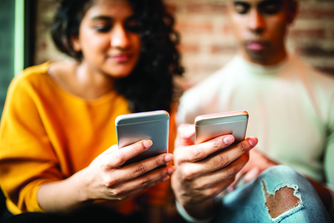 A young woman and man both on their mobile phone