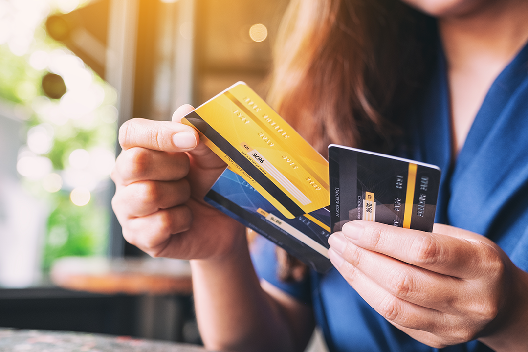 Close up of a lady holding three credit cards while grabbing one
