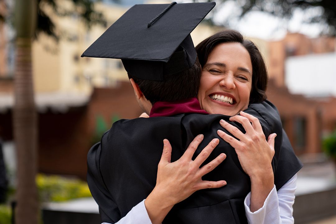 A smiling woman hugging a graduate student