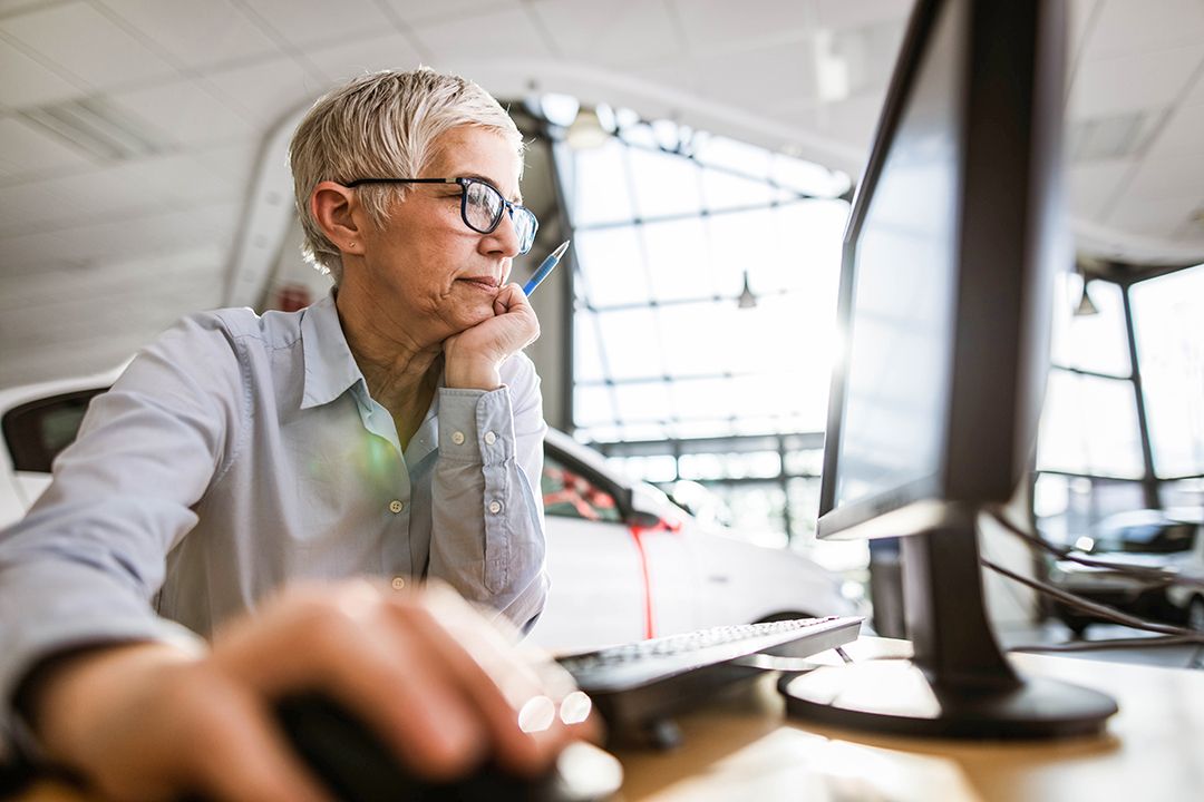 Older person working on a desktop with a hand on a mouse