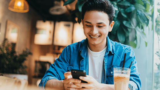 Young Asian man sitting in a cafe and on his phone