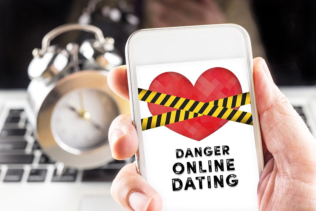 Close up of someone holding a mobile device that says danger online dating