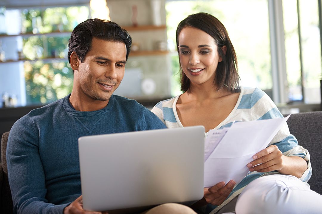 Couple looking at their laptop and papers