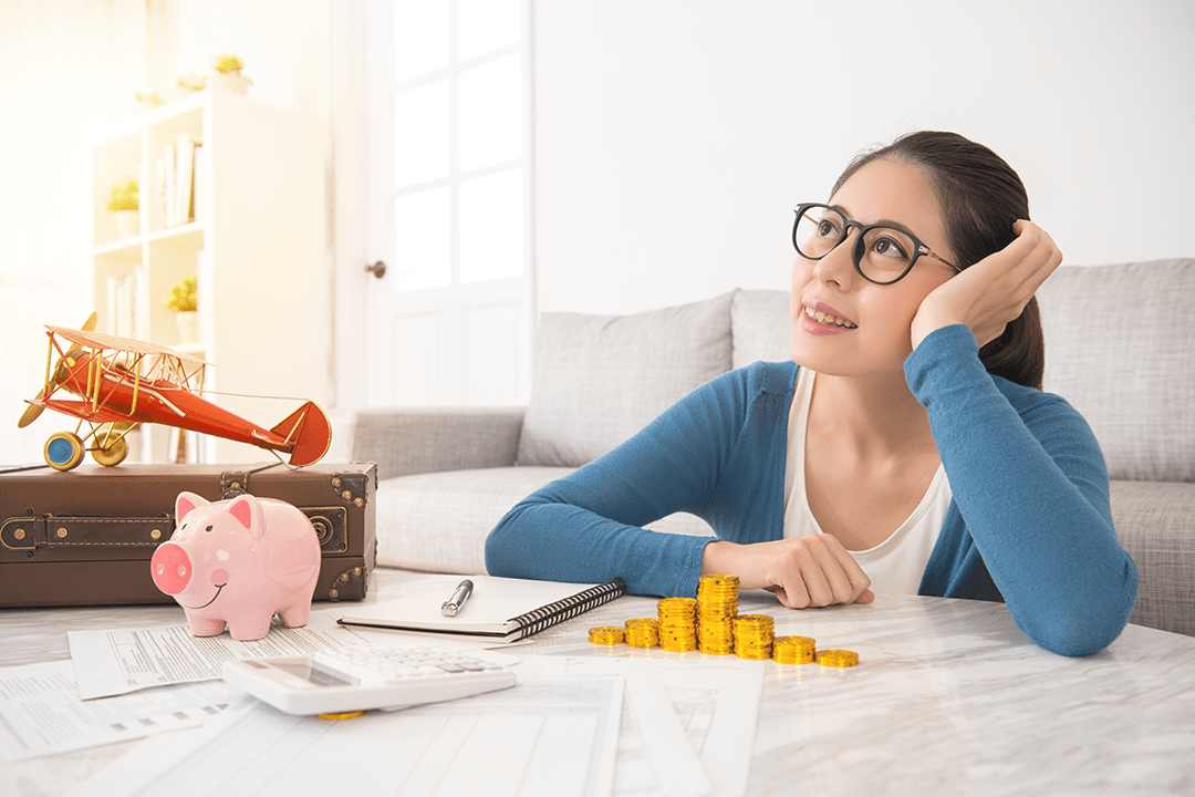 Young girl sitting at the table with money and a piggy bank