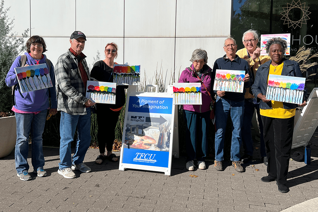 Group of older people holding painted canvases