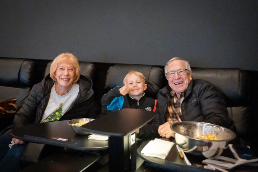 Grandparents sit with their grandson in a movie theater