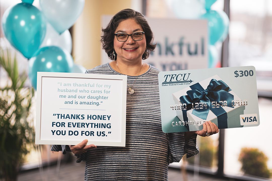 A woman smiling and holding up a frame and a large Visa card sign