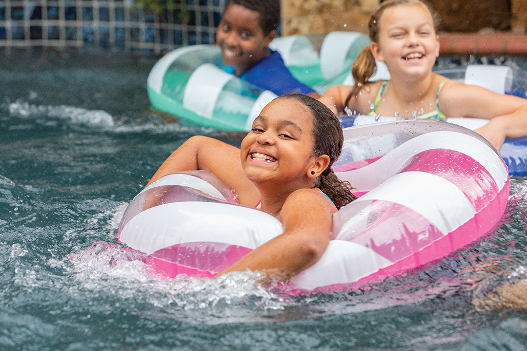 Three children in a pool with floaties