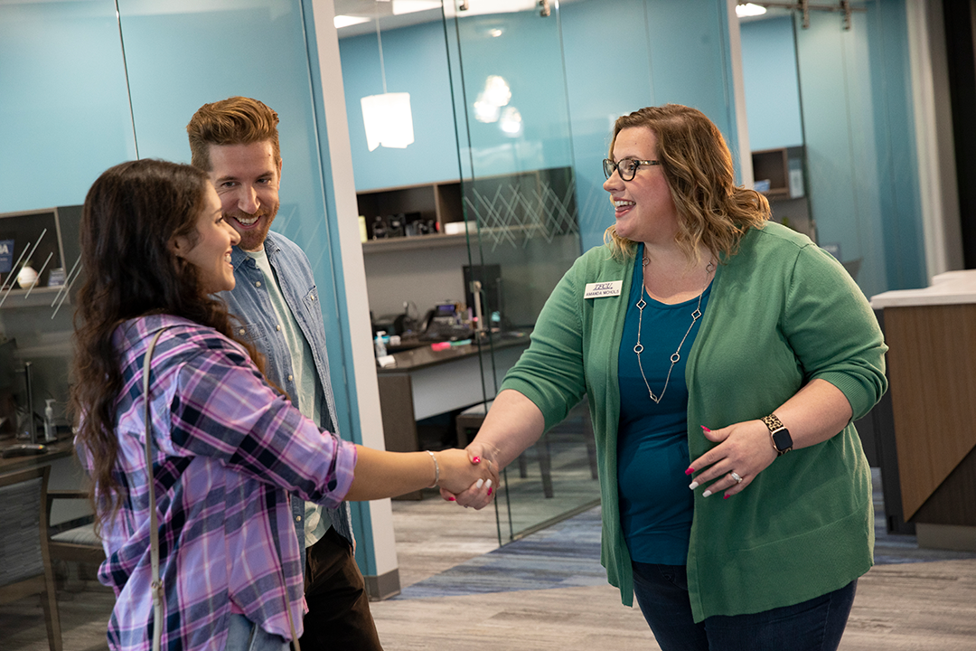 A TFCU employee shaking the hand of members in a branch.