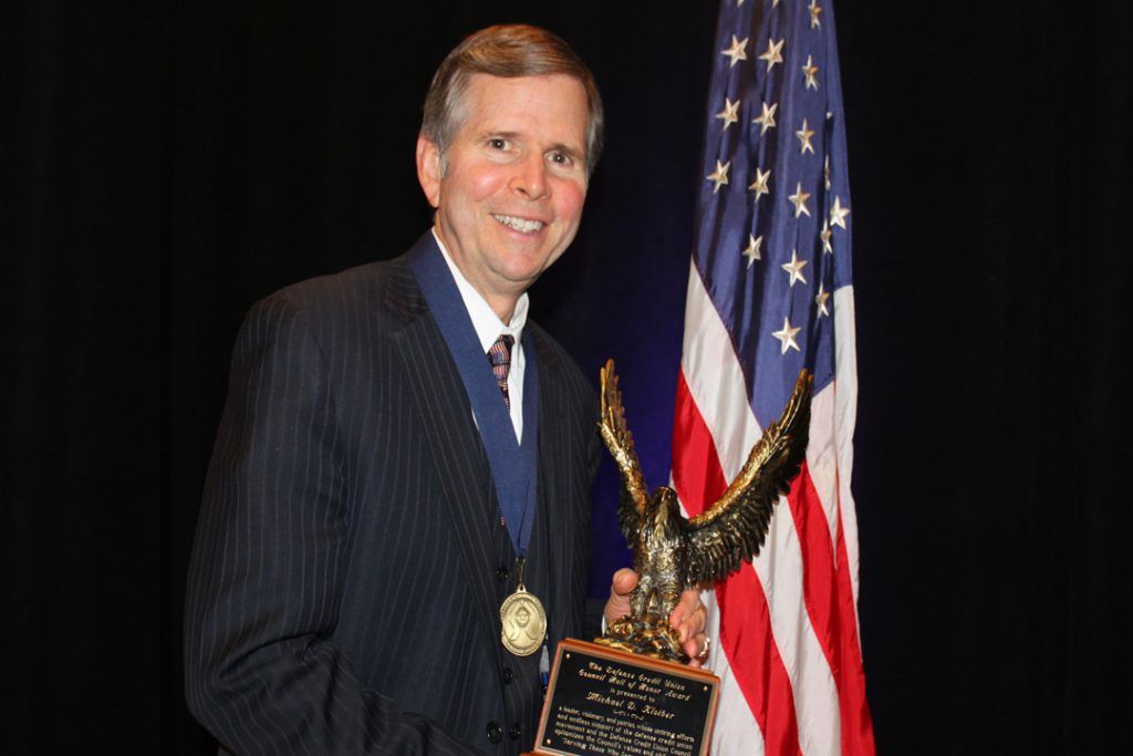 Mike Kloiber holding a trophy with a flag in the background