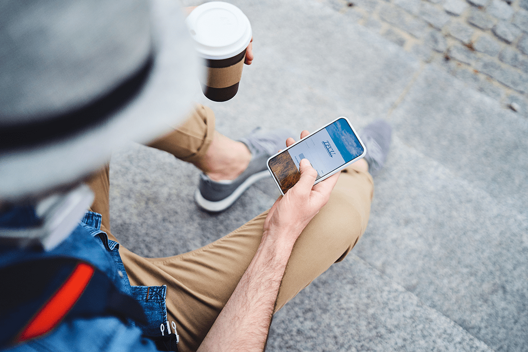 Close up of someone holding a coffee cup and a mobile device