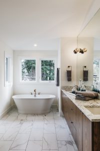 Spacious bathroom with marble floors, granite countertops and a large bathtub.