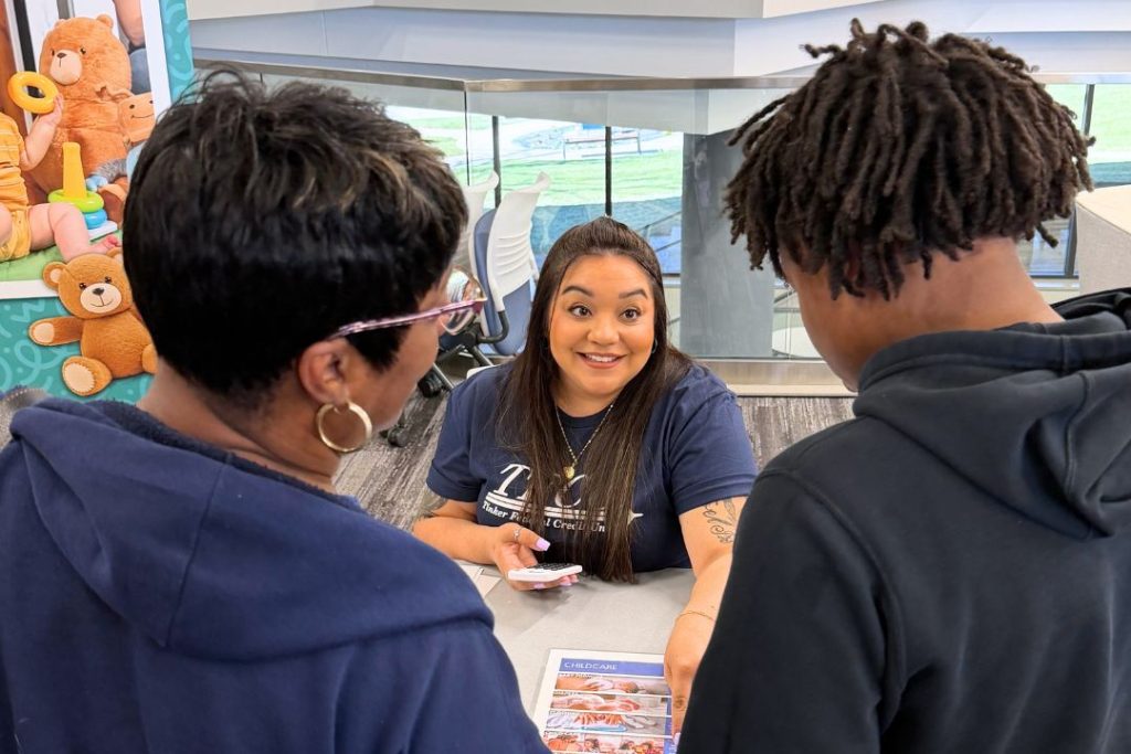 A TFCU employee points to a paper for a parent and teen