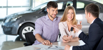 Couple at auto dealership buying a new sedan