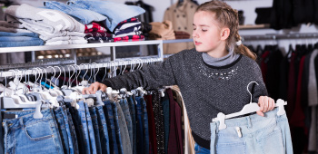 teenage girl shopping for jeans, contemplating between two differently priced items