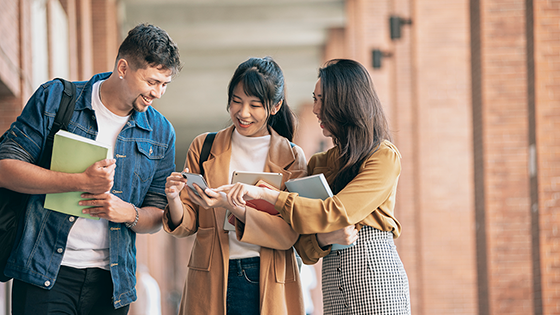 three college kids talking looking at cell phone on campus