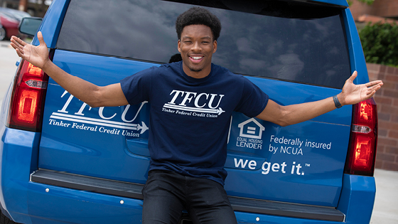 employee wearing tfcu shirt standing behind tfcu car