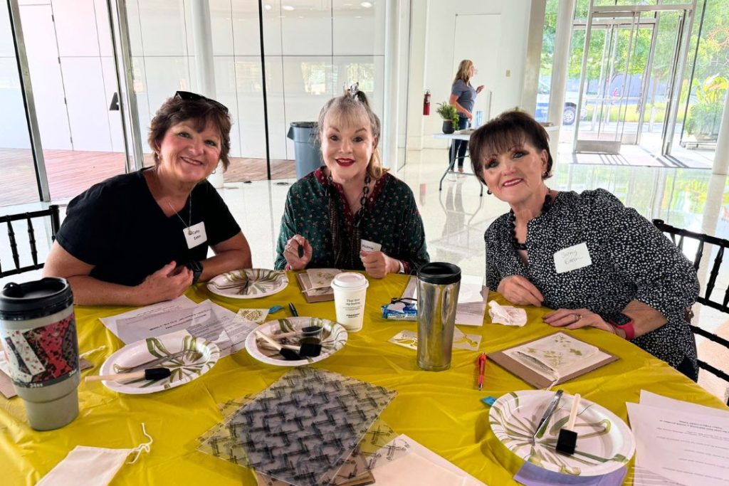 3 seniors sit at a table and do a craft