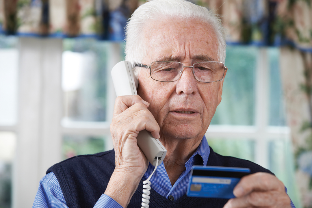 Senior man making a credit card payment over the phone.