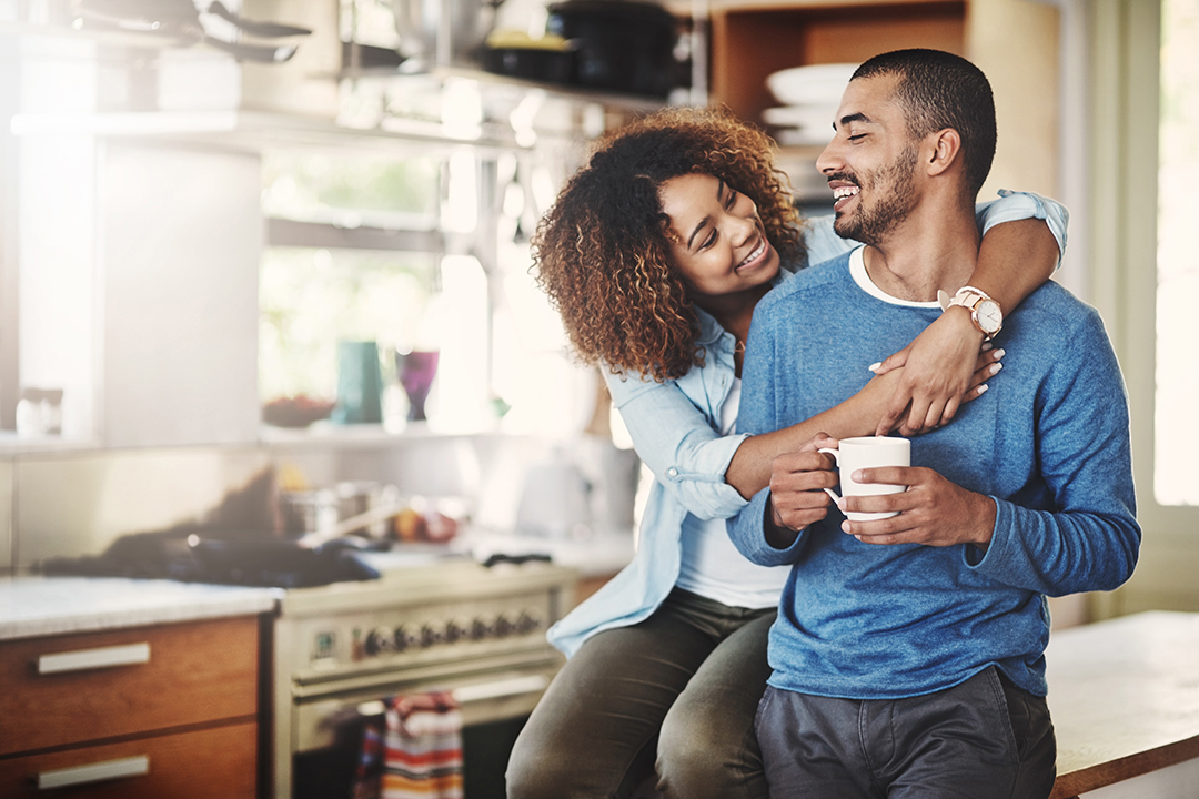 Happy young couple drinking coffee and relaxing in their kitchen.