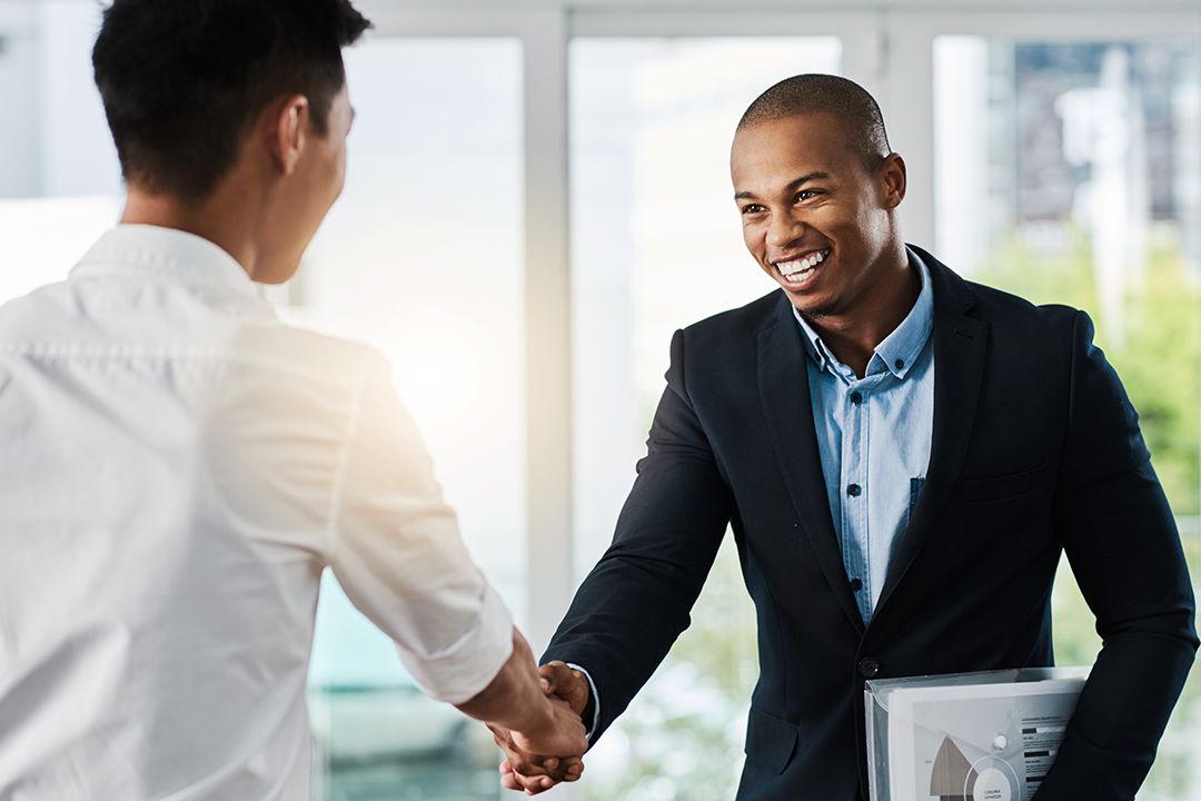 Shot oTwo young businessmen shaking hands in a modern office