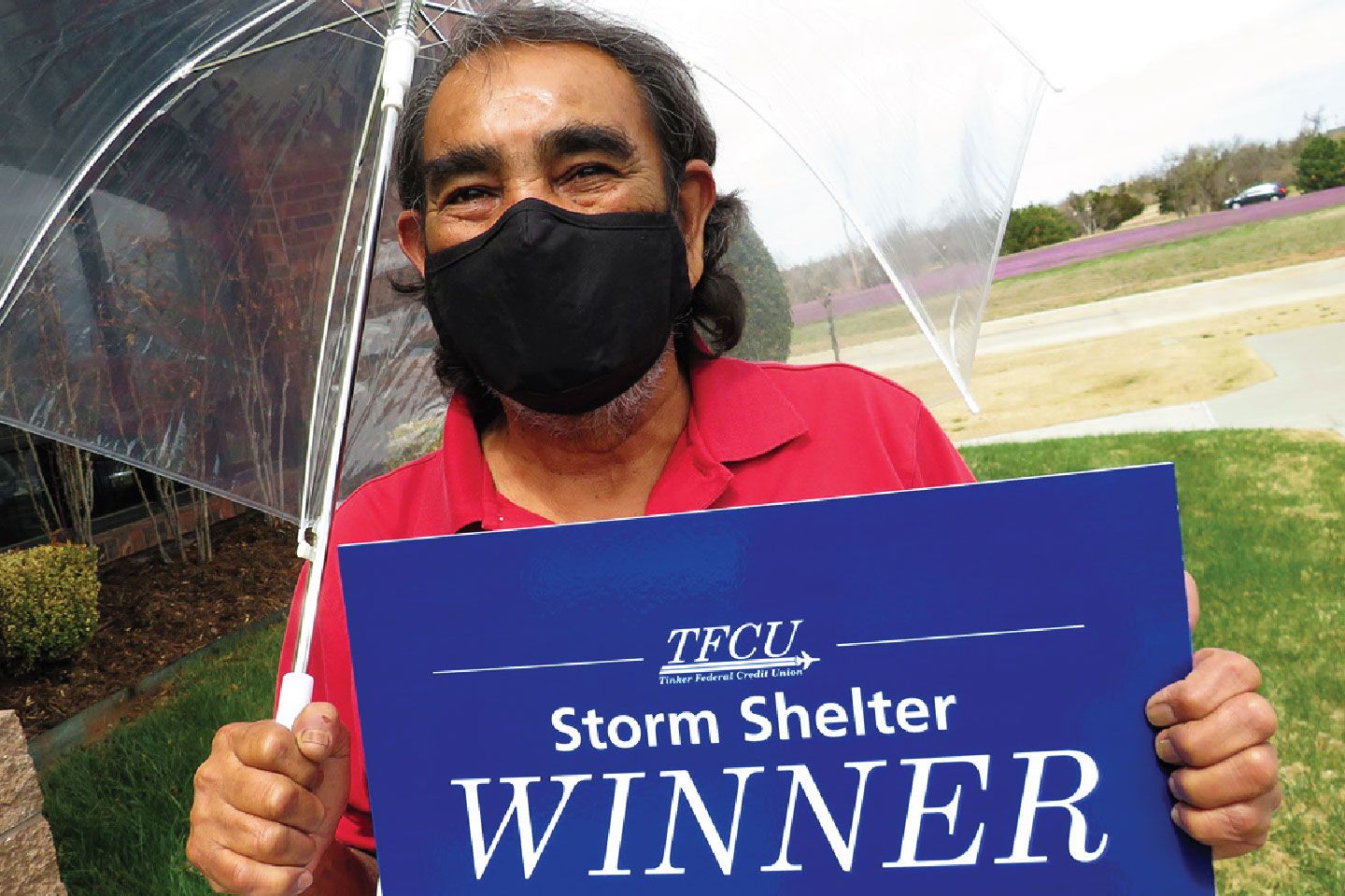 A man in a mask holding an umbrella and a sign