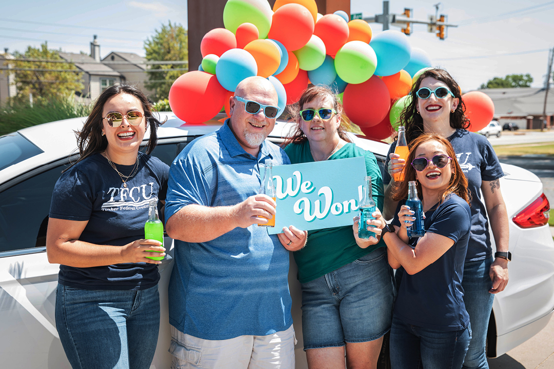 Group of people in front of a car and balloons