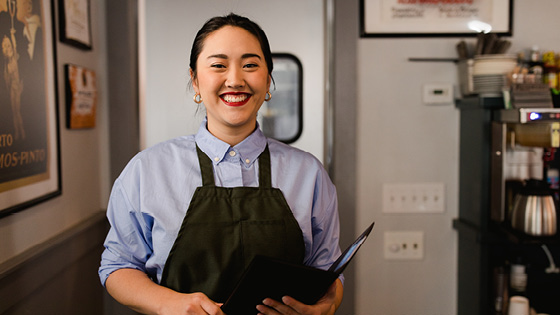 A young server woman smiling at the camera while working in a restaurant