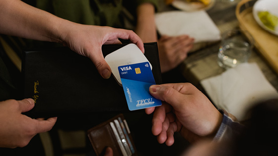 Close up of someone holding a TFCU MoneyPlus card to a card reader to pay for something