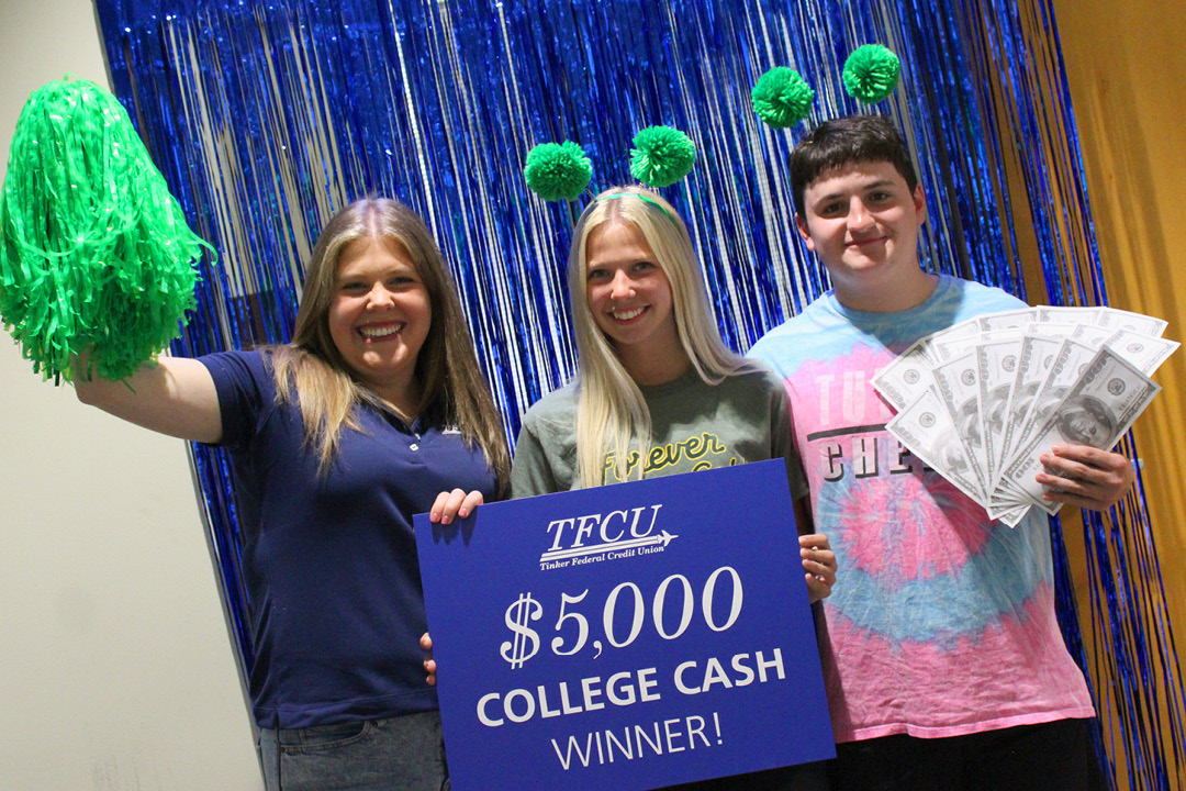 Young woman who is a student is standing with a family member and TFCU employee while holding up a sign that says $5,000 college cash winner