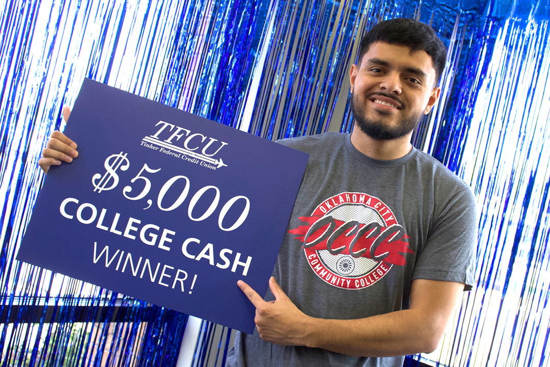Young man who is a student holding up a sign that says $5,000 college cash winner