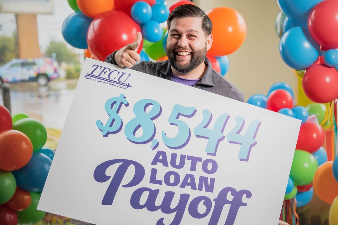 A man holding a sign and pointing to the camera in excitement