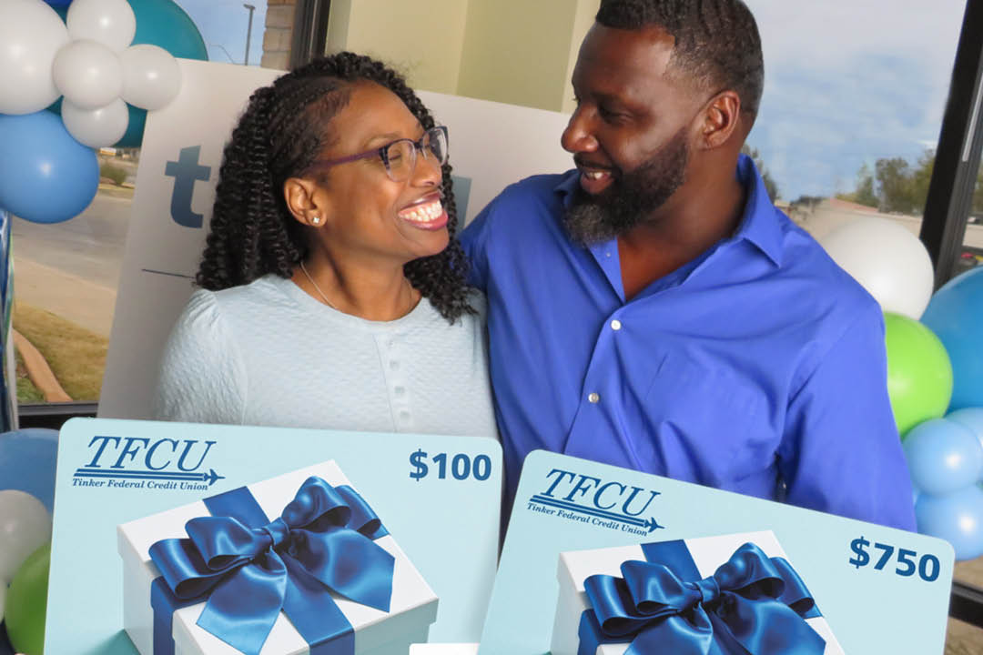 A wife and husband who are Thankful for You winners are looking at each other while both are holding up a sign.