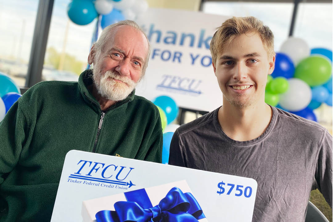 A father and son who are Thankful for You winners looking at the camera and holding up a sign