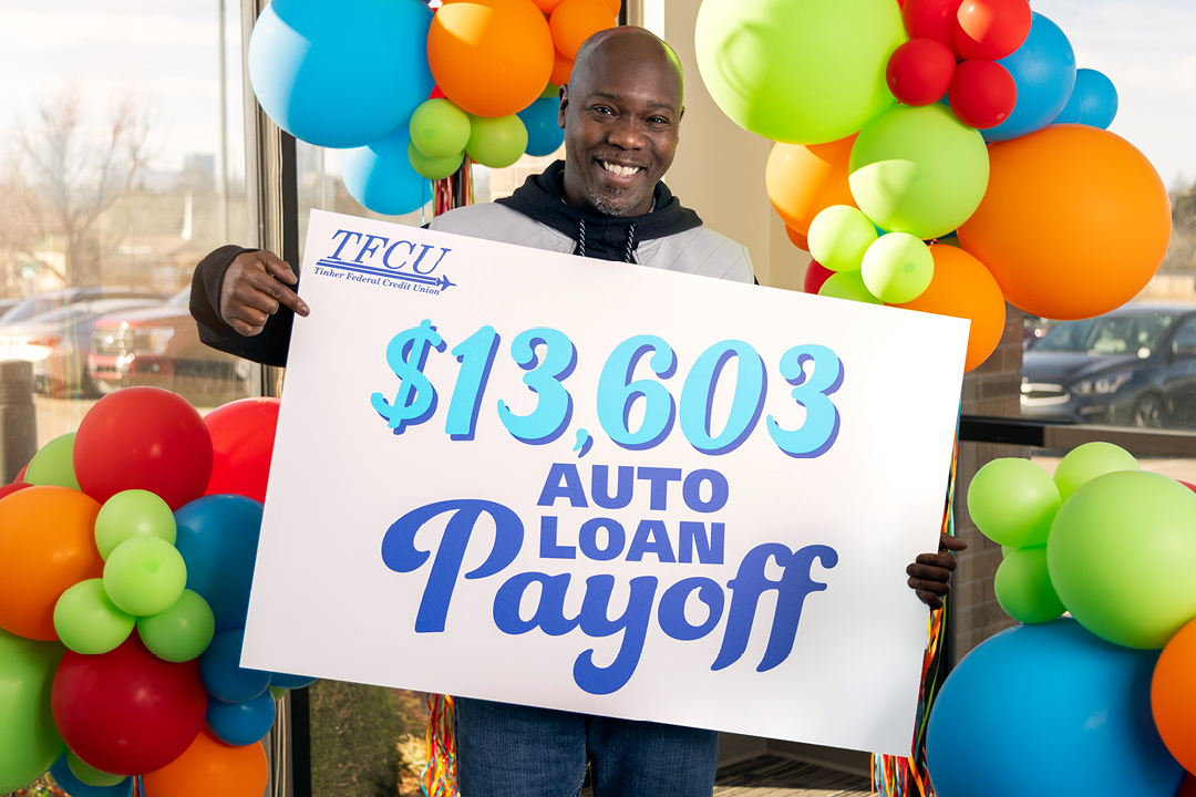 A man holding a sign that says $13,603 auto loan payoff
