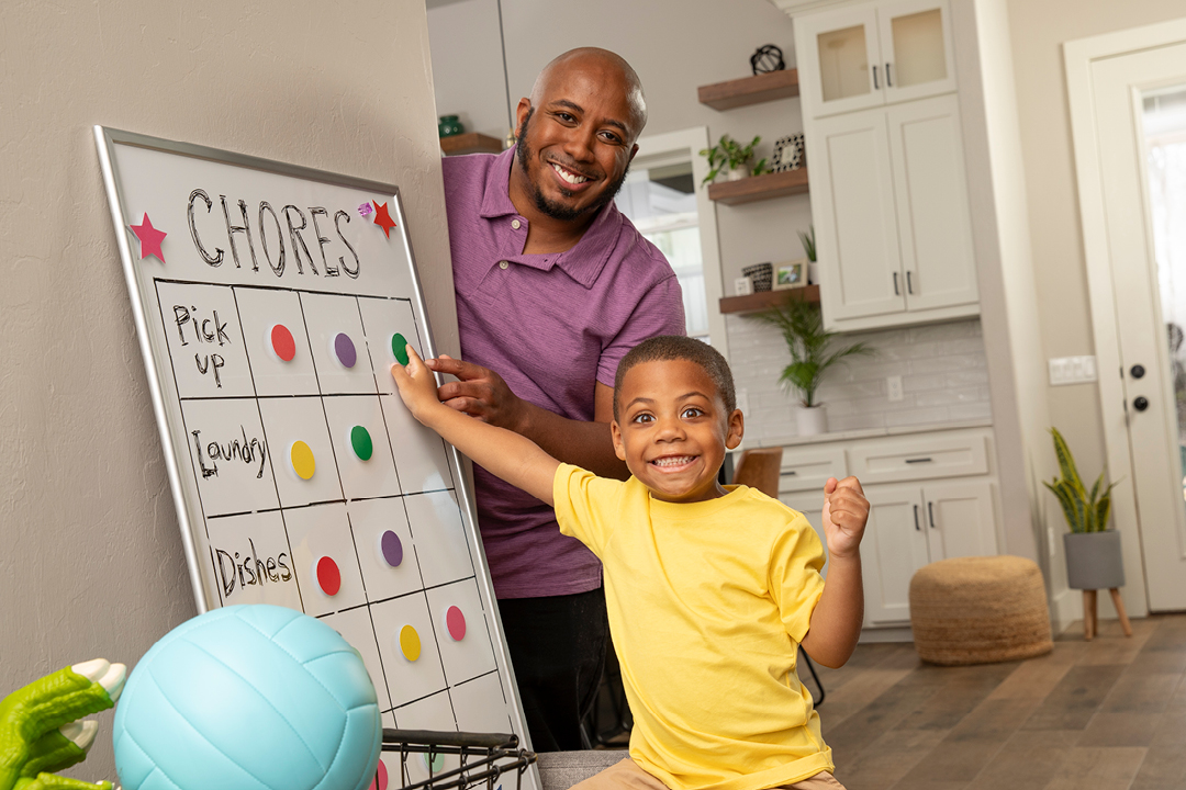 A dad and son smiling at the camera while playing with a white board