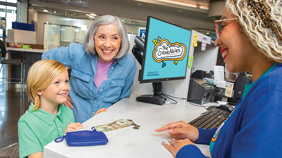 A TFCU employee looking at a child with his mom next to him.